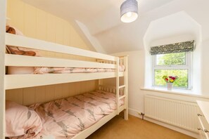 A bunk bed room with a window and radiator.