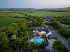 A large estate with a swimming pool, multiple buildings, and expansive green fields.