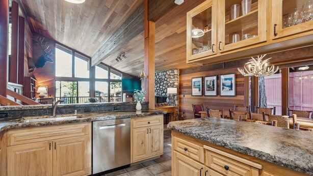 A spacious kitchen with granite countertops, wooden cabinets, and a stainless steel dishwasher.