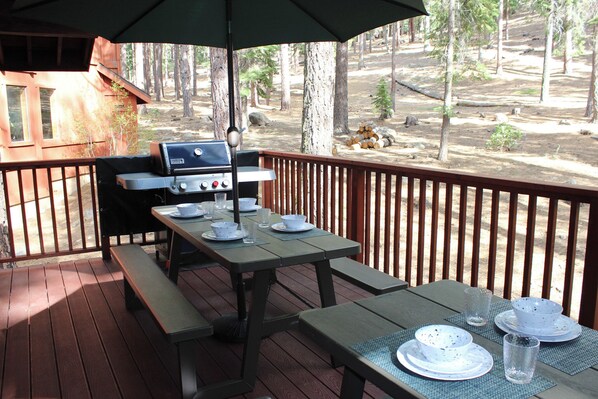 An outdoor deck with a grill, picnic table, and benches.