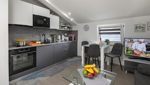 Eine moderne Küche mit integrierten Geräten, ein Essbereich mit Fernseher und Blick ins Freie.