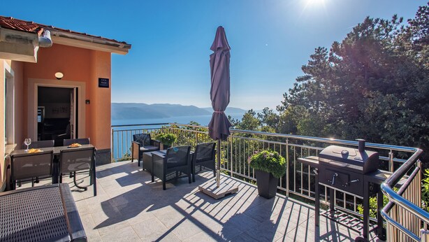 Eine Terrasse mit Gartenmöbeln, einem Grill und Bergblick.