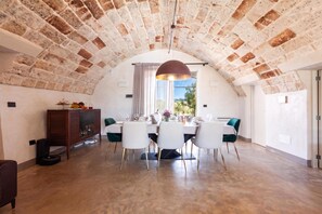 A dining area with a brick ceiling, white walls, and a large window.