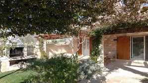Un espace extérieur aménagé avec un sol en pierre, une pergola et un coin salon.