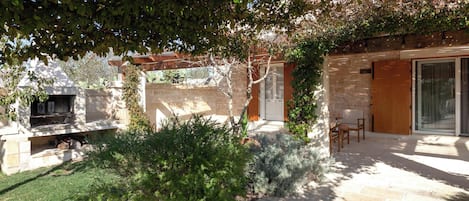 A patio area with stone flooring, a pergola, and a seating arrangement.