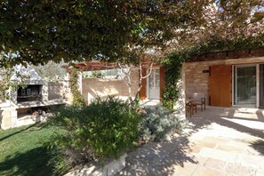 Un espace extérieur aménagé avec un sol en pierre, une pergola et un coin salon.