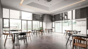 A spacious dining area with multiple tables and chairs, large windows offering views of the outside, and a modern ceiling design with recessed lighting. - The Sky 89 Panorama D7 (Ho Chi Minh City)