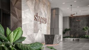 A modern reception area with a geometric marble wall, a large black marble reception desk, and indoor plants. - The Sky 89 Panorama D7 (Ho Chi Minh City)