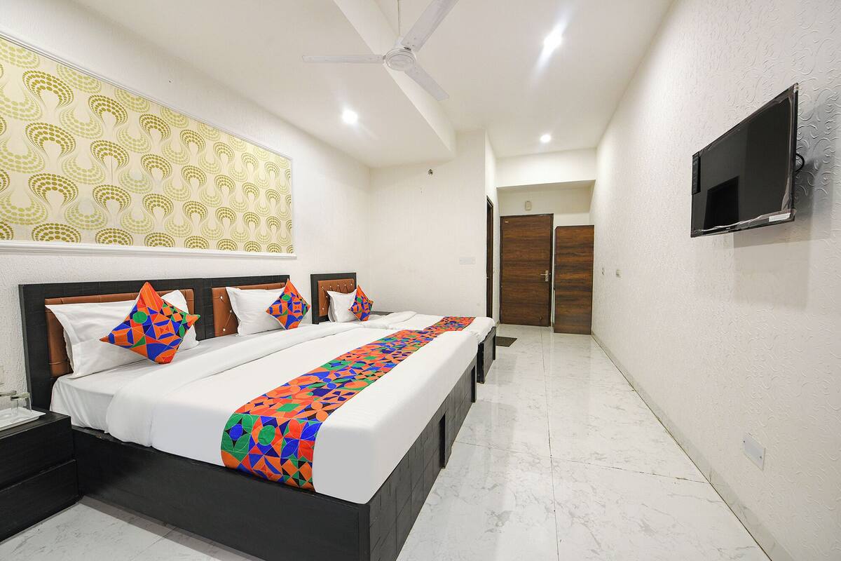 A hotel room with a large bed, a ceiling fan, a TV mounted on the wall, and a patterned wallpaper.