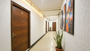 Un couloir avec des portes en bois, une plante en pot et une œuvre d’art abstrait accrochée au mur.