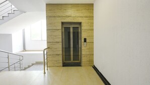 Un intérieur moderne avec un escalier, un ascenseur fixé au mur et un design épuré et minimaliste.