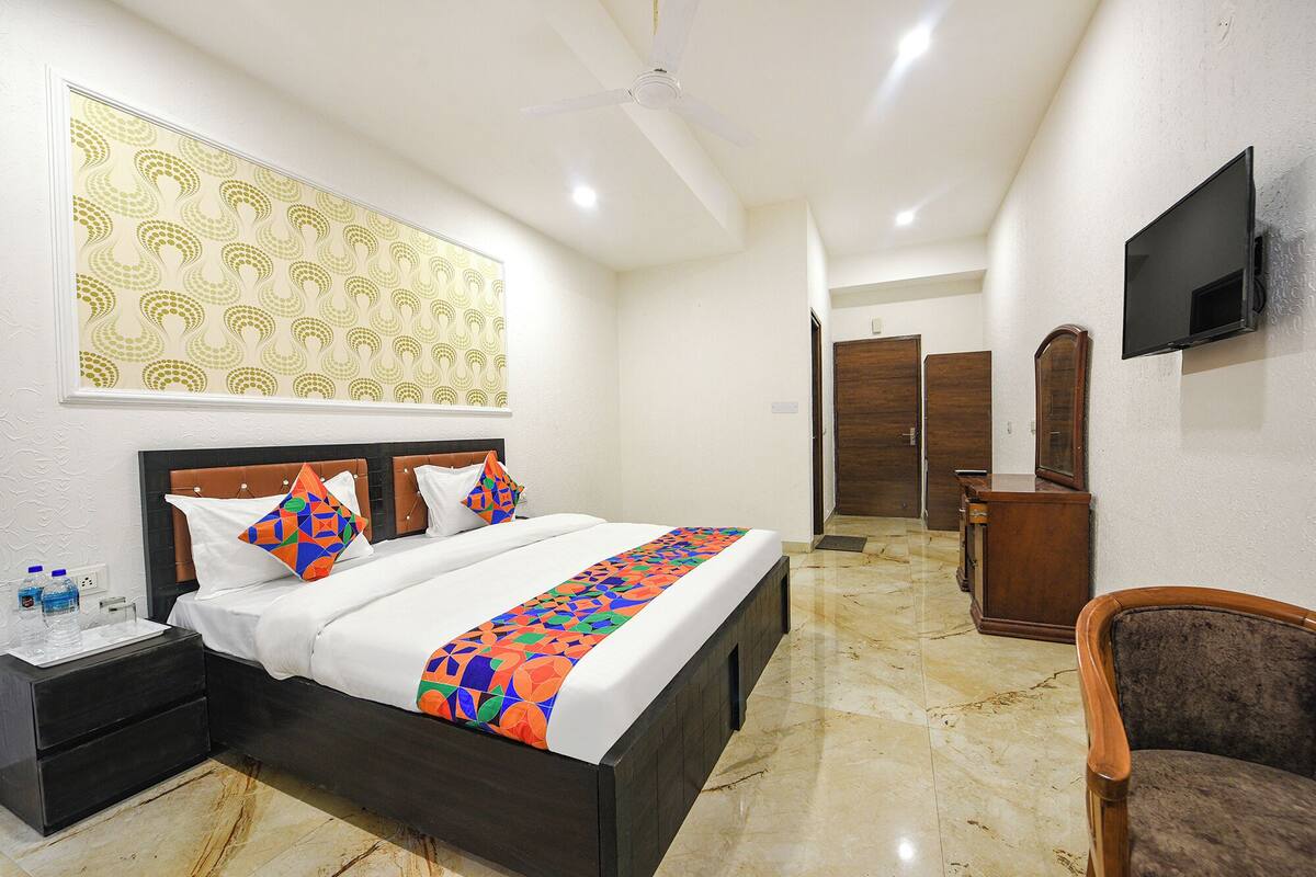 A hotel room with a bed, a nightstand, a chair, a television, and a ceiling fan.