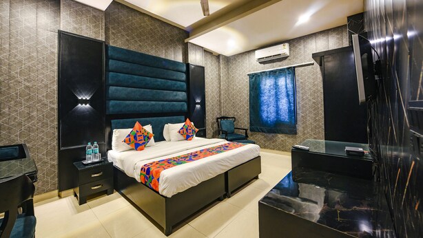 A modern hotel room with a large bed, a flat-screen TV, a desk with a chair, and a ceiling fan.