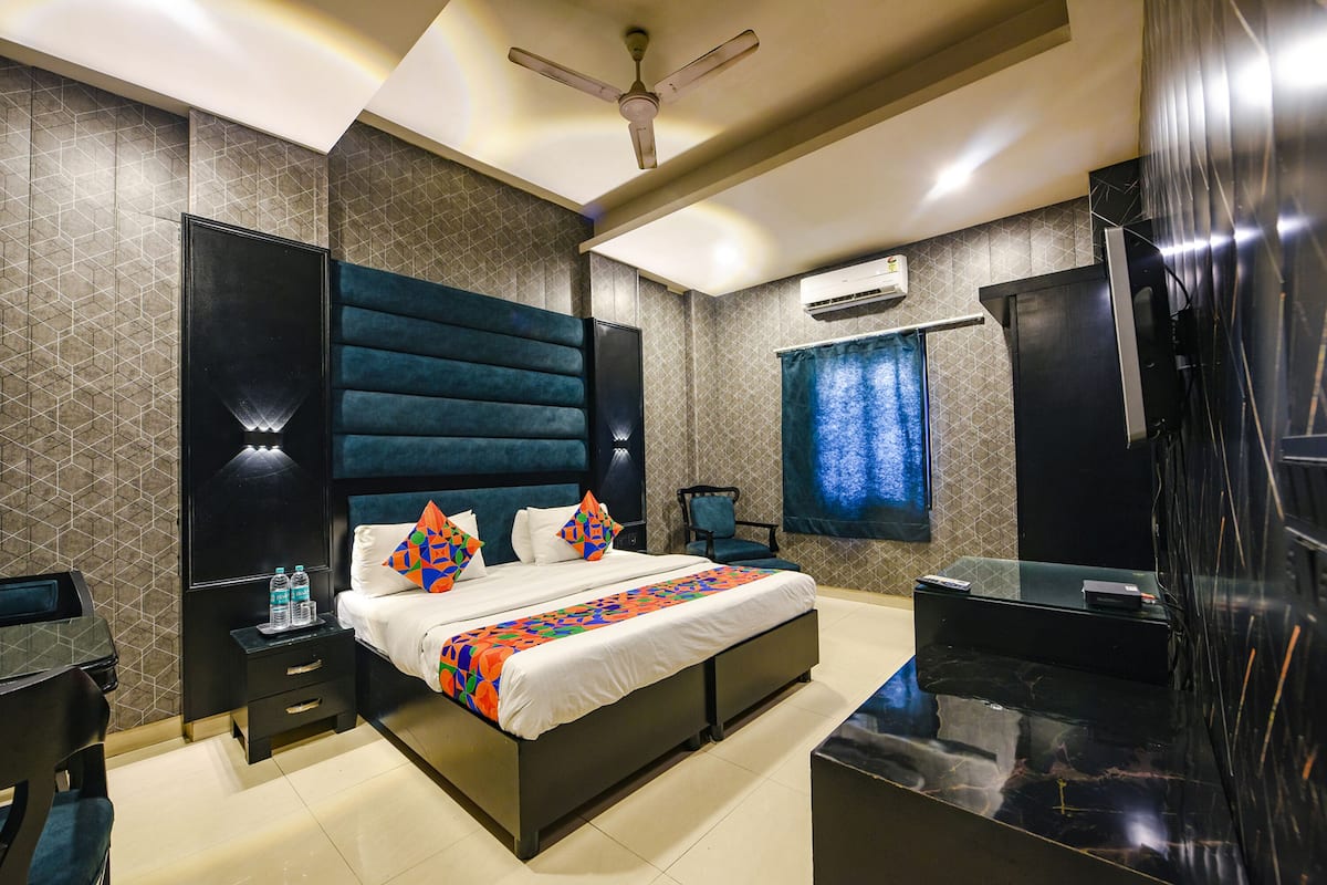 Une chambre d’hôtel moderne dotée d’un grand lit, d’un téléviseur à écran plat, d’un bureau avec une chaise et d’un ventilateur de plafond.