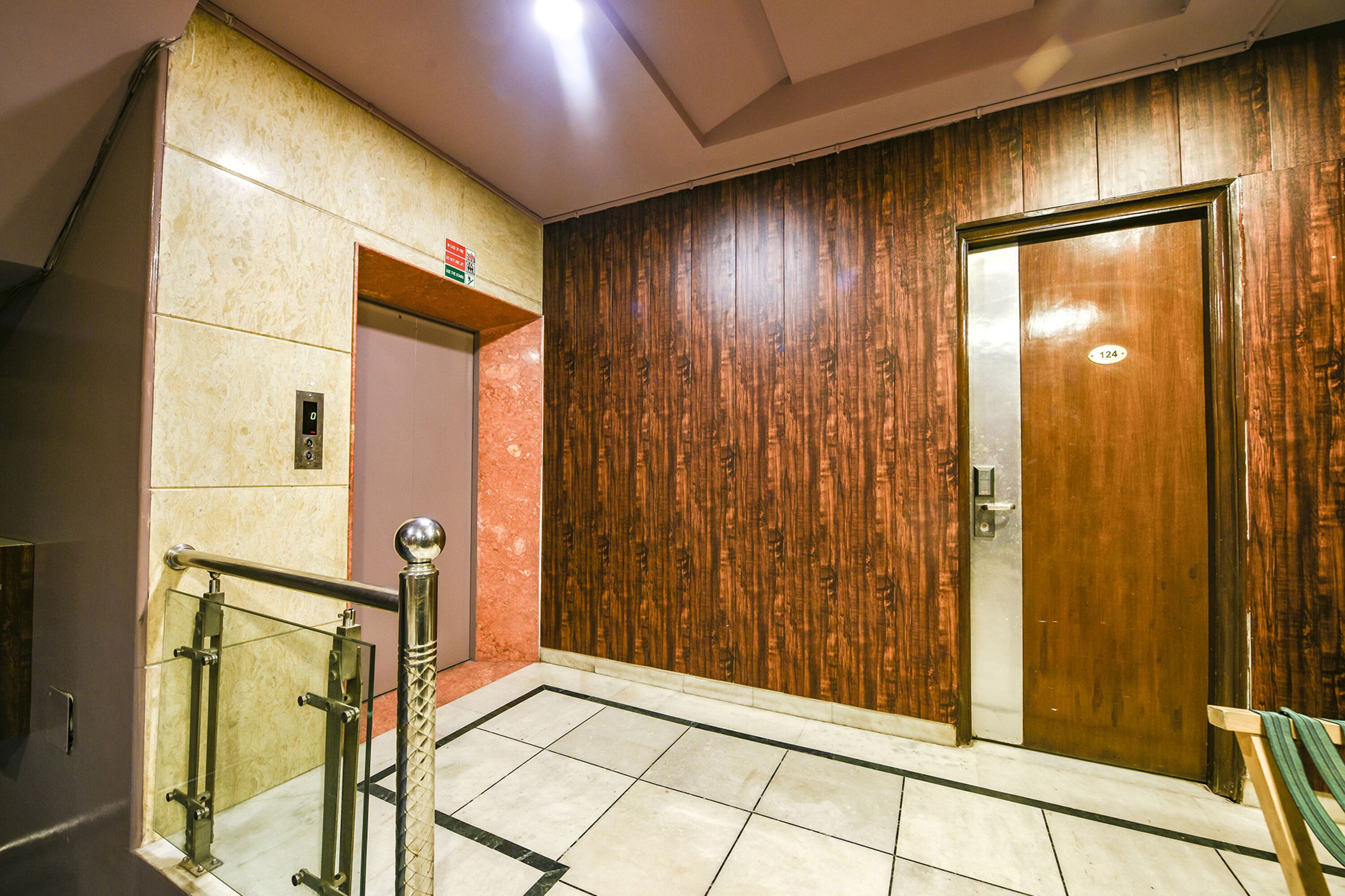 Eine Hotellobby mit einer Holzwand, einem Marmorboden und einer Holztür mit der Nummer 124.