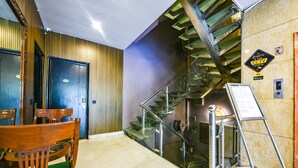 A hotel lobby with a staircase, a reception desk, and a wooden chair.