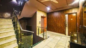 A staircase with glass railings, a ceiling fan, and a wooden door.