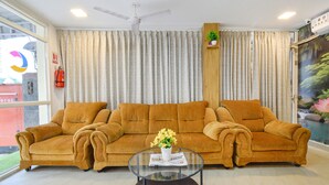 Ein Wohnzimmer mit einer Couch, einem Glastisch mit Blumenvase und einem Deckenventilator.