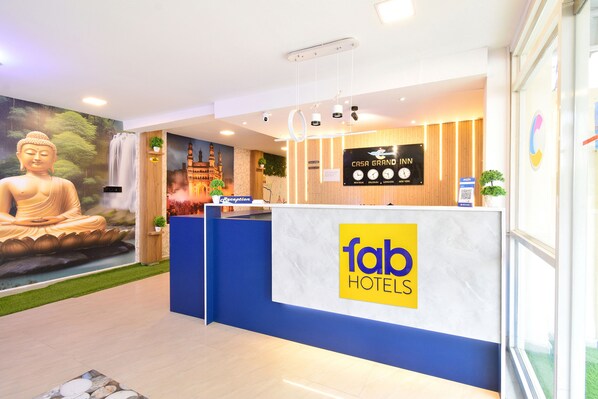 A reception area with a Buddha statue, a reception desk, and a wall with a cityscape mural.