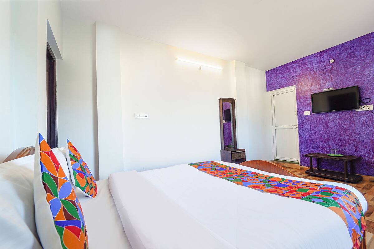 Een hotelkamer met een bed, een televisie en een paarse muur.