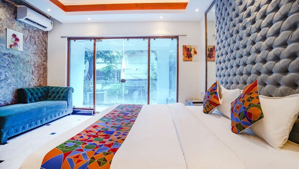 Une chambre d’hôtel moderne avec un grand lit, un canapé bleu et une vue à travers la porte vitrée.