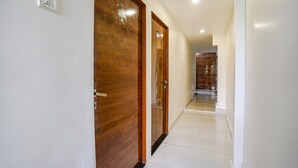 Un couloir avec des portes en bois et un interrupteur sur le mur.