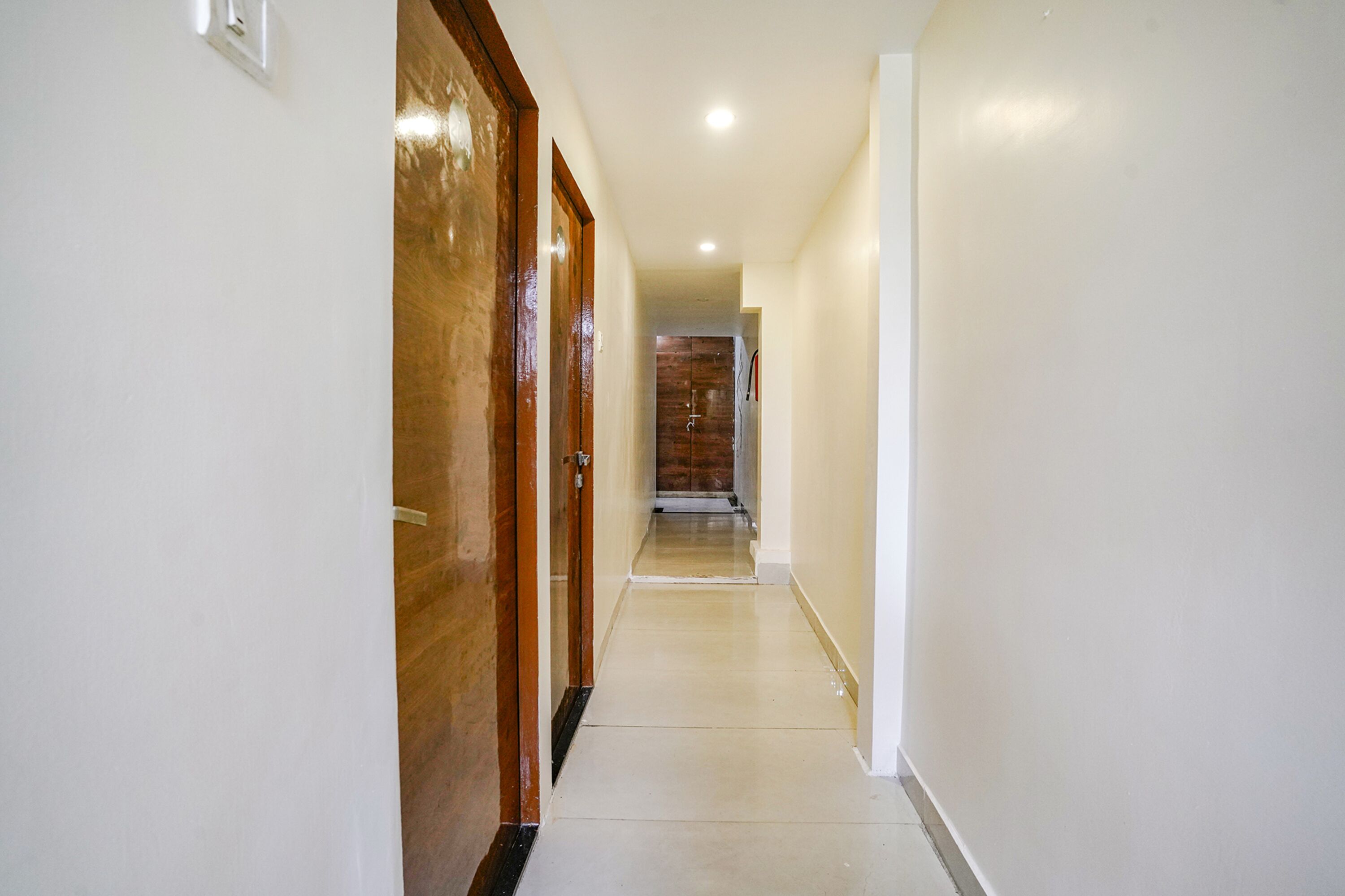 A hallway with a wooden door on the left and a white wall on the right.