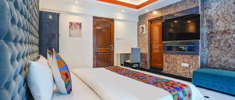 A hotel room with a large bed, a ceiling fan, a TV, and a seating area with a blue sofa.