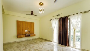 A spacious room with a marble floor, a wooden wall unit, a ceiling fan, and a window with curtains. - Fabhotel Lucky Inn Grand Residency (Chennai)