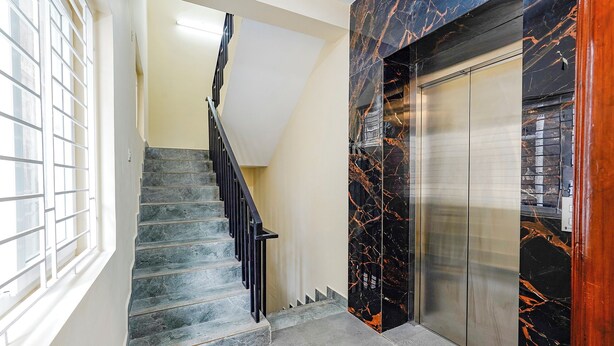 A staircase with a marble wall and an elevator. - Fabhotel Lucky Inn Grand Residency (Chennai)