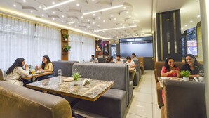 Um restaurante moderno com disposição de assentos, incluindo sofás e mesas, e um teto com iluminação embutida.