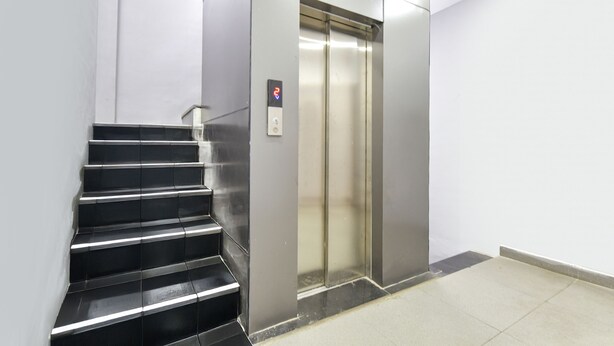 Ein moderner Aufzug mit Bedienfeld und einer Metalltreppe.