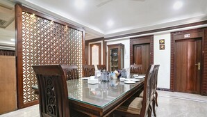 A dining area with a glass-top table, wooden chairs, and a decorative partition. - Fabhotel Welcome Apartments (Mumbai)