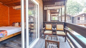Una cabaña de madera con balcón, una cama, dos sillas y una mesa.