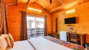 Una habitación de cabaña de madera con una cama, un televisor y un escritorio pequeño.