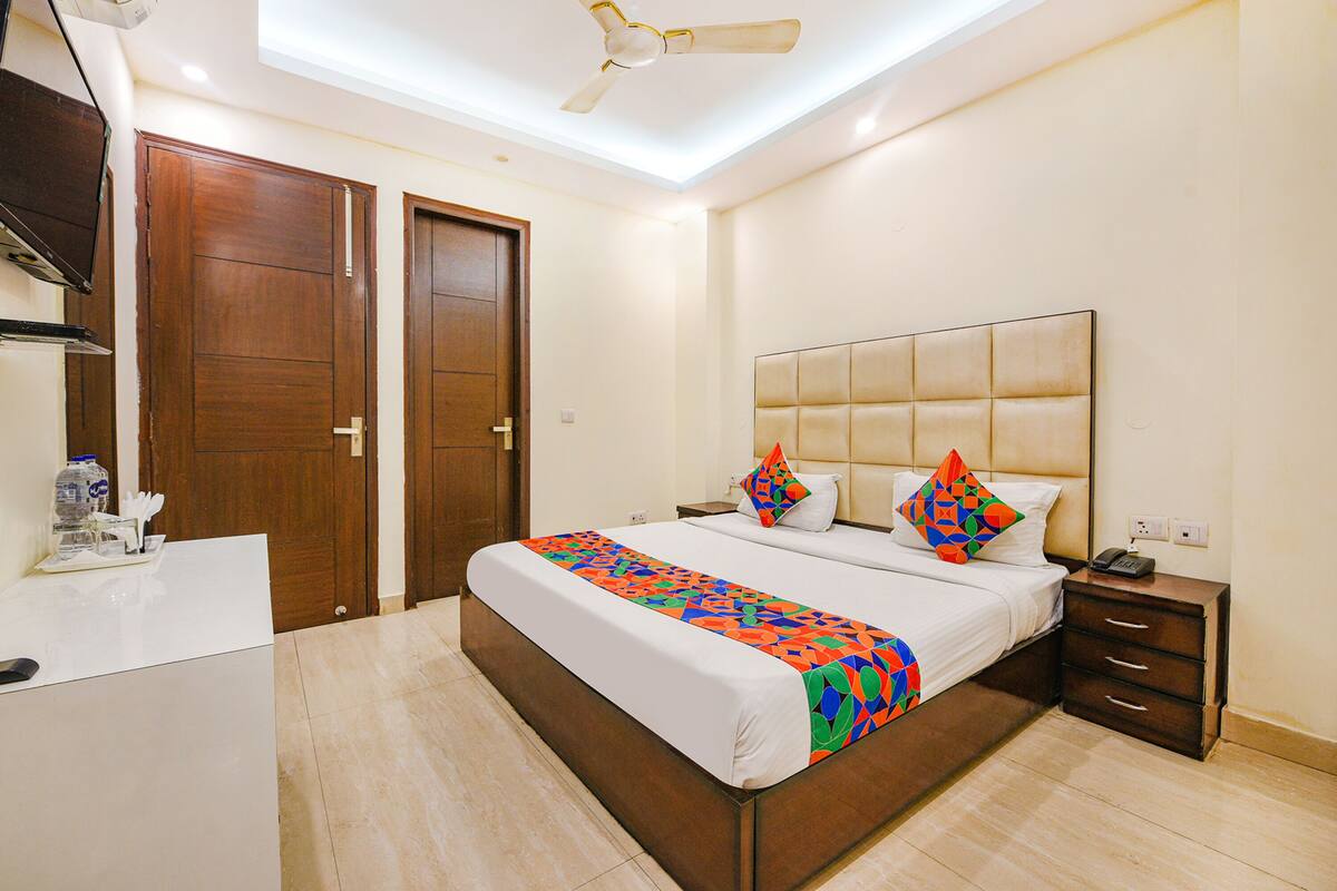 A hotel room with a bed, bedside tables, a desk, and a ceiling fan.