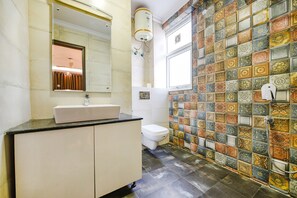 A bathroom with a tiled shower wall, a sink, and a toilet. - Fabhotel Ak Villa (New Delhi)