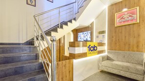 A hotel reception area with a staircase, reception desk, and a sofa. - Fabhotel Lfc (Jaipur)