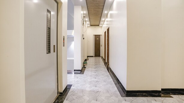 A hallway with a patterned floor, white walls, and a ceiling with recessed lighting.