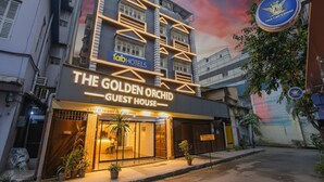 A hotel named "The Golden Orchid Guest House" with a modern facade and neon signage.