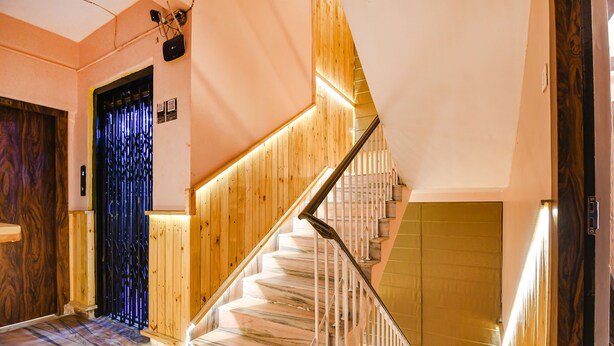 A staircase with wooden steps and a metal railing, leading to a landing with a door.