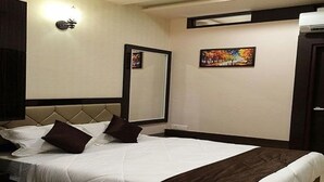 A hotel room with a bed, a large mirror, and a painting on the wall. - Fabhotel Purvika (Varanasi)