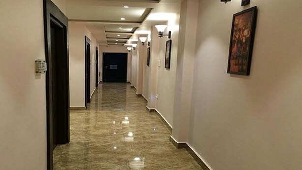 A long, narrow hallway with a polished marble floor and light-colored walls. - Fabhotel Purvika (Varanasi)