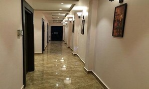 A long, narrow hallway with a polished marble floor and light-colored walls. - Fabhotel Purvika (Varanasi)