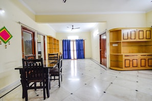 A spacious dining area with a long table and chairs, a ceiling fan, and wooden cabinets. - Fabhotel Merit Suites (Hyderabad)