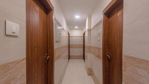 A corridor with wooden doors and tiled walls, leading to a room with a tiled floor.