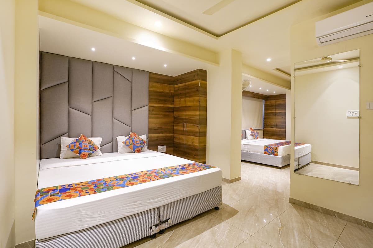A modern hotel room with a large bed, a wooden accent wall, and a mirror.