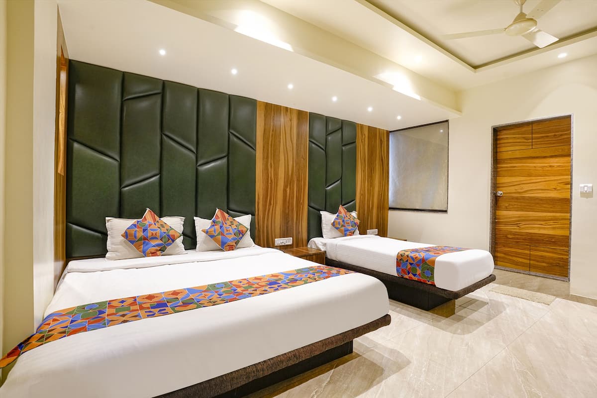 A hotel room with two beds, a wooden headboard, a large mirror, and a wooden door.