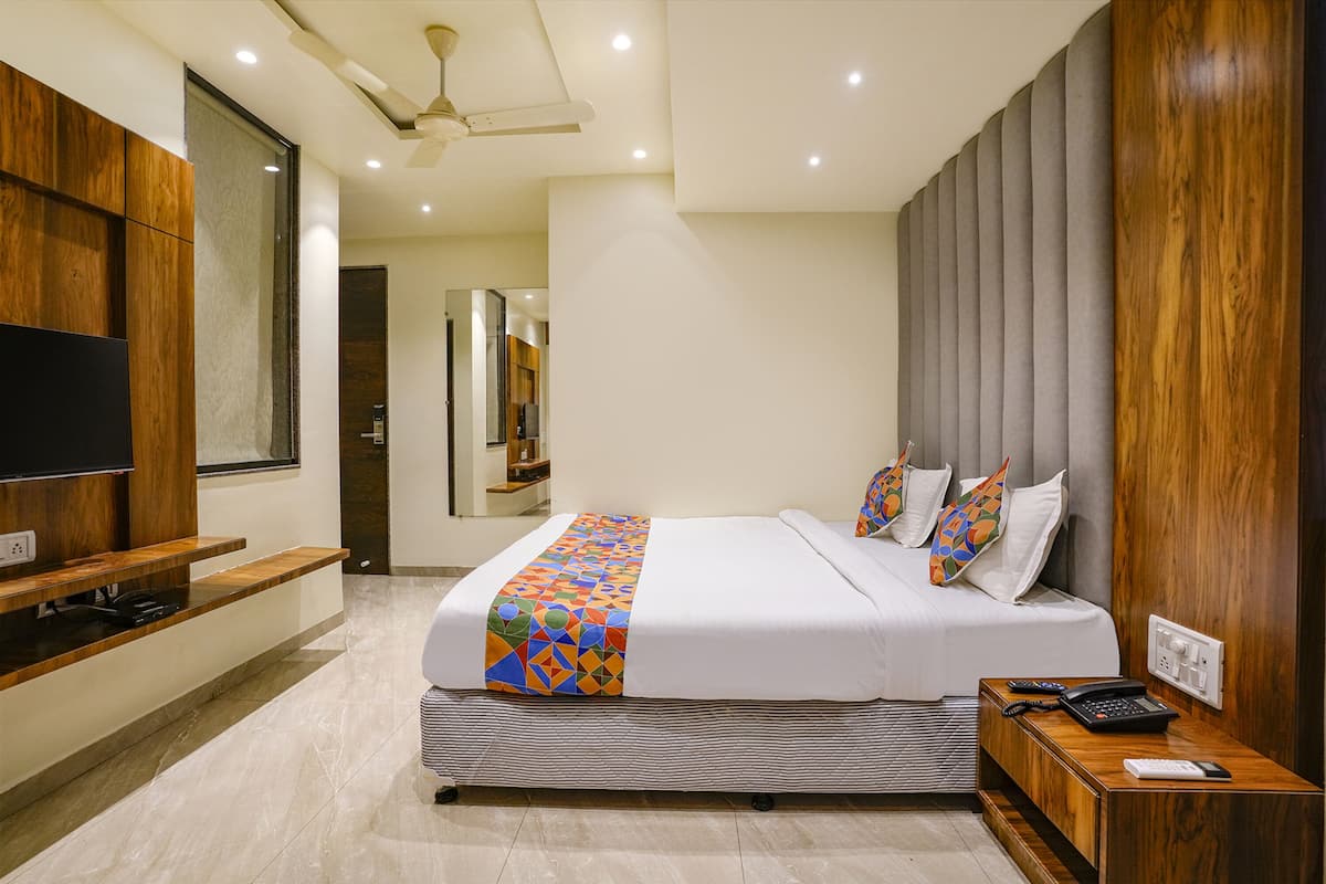 A modern hotel room with a large bed, a flat-screen TV, a wooden console table, and a telephone.