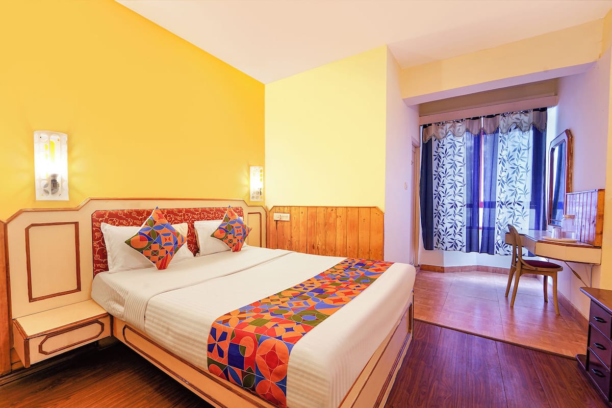 A hotel room with a wooden bed, a desk, and a chair.